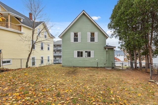 rear view of house featuring a lawn and a balcony