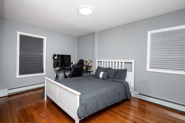 bedroom with dark hardwood / wood-style floors and baseboard heating