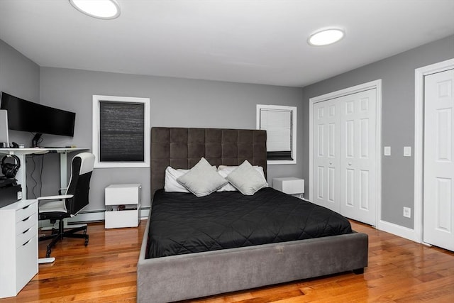 bedroom with a baseboard heating unit and light wood-type flooring