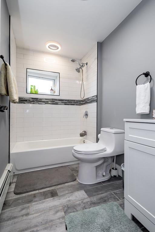 full bathroom featuring tiled shower / bath, vanity, toilet, and a baseboard heating unit