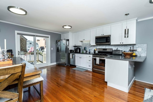 kitchen featuring crown molding, dark hardwood / wood-style floors, white cabinets, stainless steel appliances, and backsplash