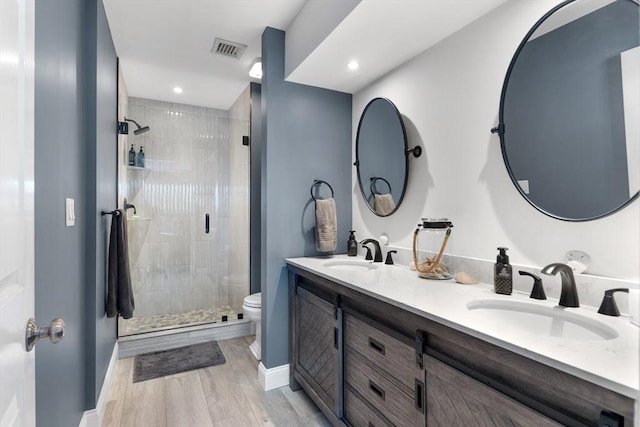 bathroom featuring vanity, toilet, a shower with door, and hardwood / wood-style floors