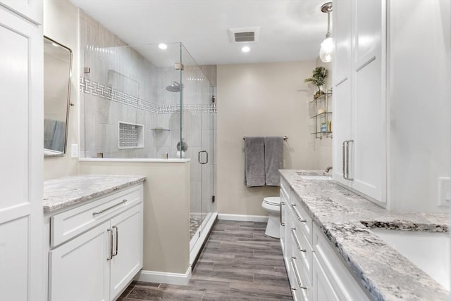 bathroom featuring vanity, hardwood / wood-style floors, a shower with door, and toilet