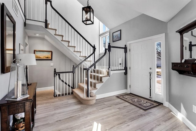 entrance foyer featuring a towering ceiling, a healthy amount of sunlight, and light hardwood / wood-style floors