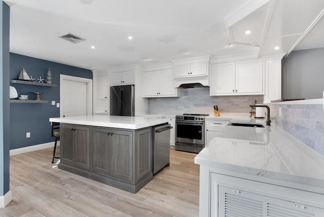 kitchen with appliances with stainless steel finishes, a center island, white cabinets, and custom range hood