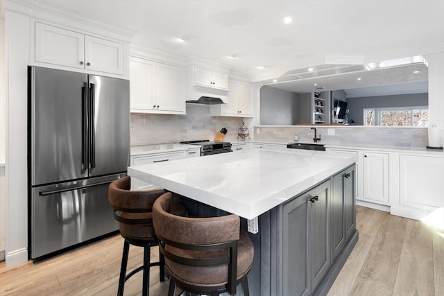 kitchen featuring white cabinetry, appliances with stainless steel finishes, a kitchen bar, and kitchen peninsula