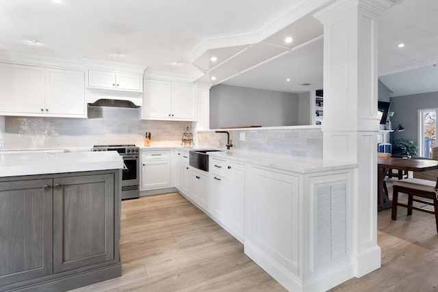 kitchen featuring stainless steel range oven, sink, ornate columns, white cabinetry, and light wood-type flooring