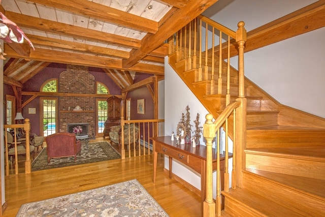 living room with vaulted ceiling with skylight, a fireplace, light wood-type flooring, and wooden ceiling