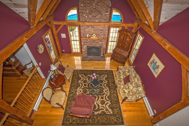 living room featuring high vaulted ceiling, a fireplace, beamed ceiling, wooden ceiling, and hardwood / wood-style flooring