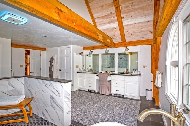 kitchen featuring vaulted ceiling with beams, white cabinetry, sink, and dark tile patterned flooring