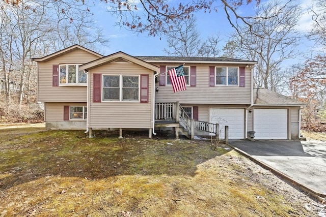 raised ranch featuring a garage and a front lawn