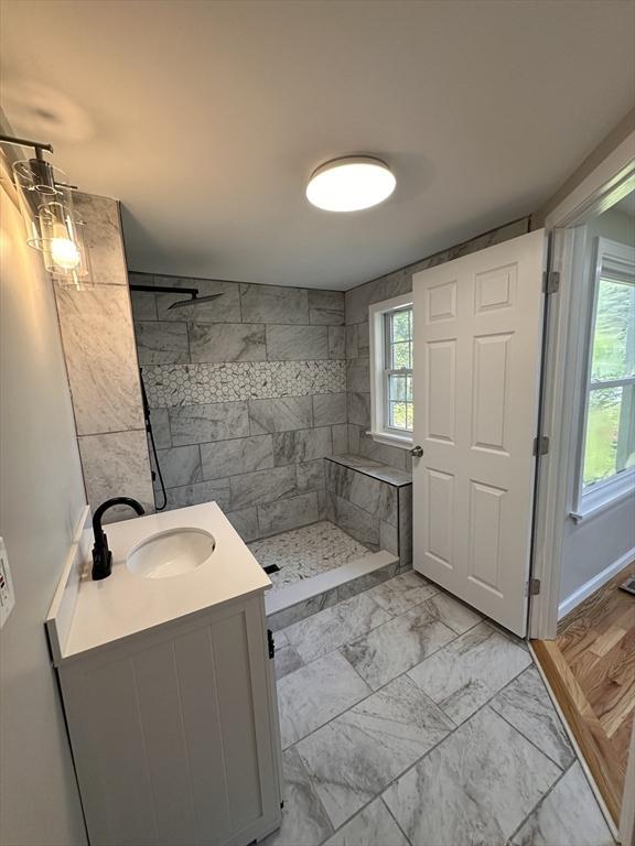 250 Gresham St, Springfield, MA 01119 - bathroom featuring marble look tile flooring, a tile shower, and vanity