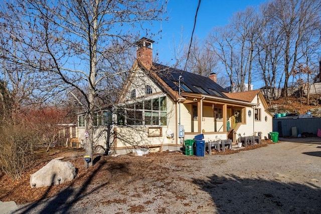 exterior space with solar panels, a chimney, and fence