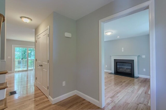 hallway featuring light wood-style floors, visible vents, and baseboards