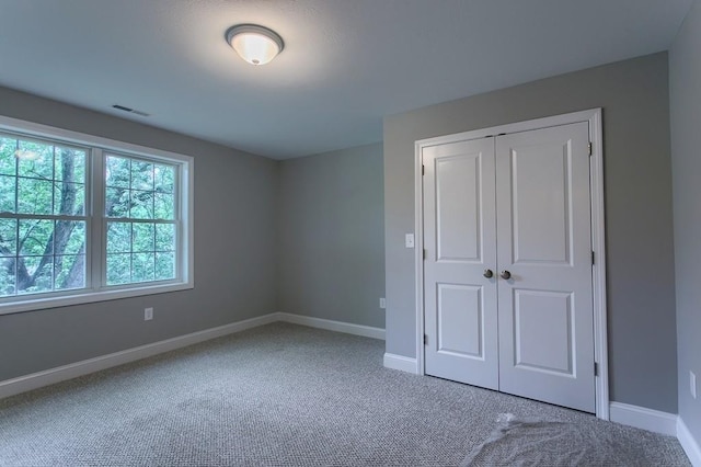 unfurnished bedroom featuring carpet, a closet, visible vents, and baseboards