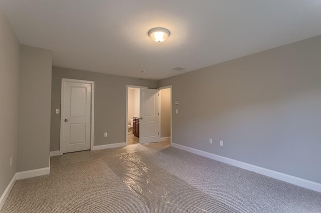 unfurnished bedroom featuring light carpet, ensuite bath, visible vents, and baseboards