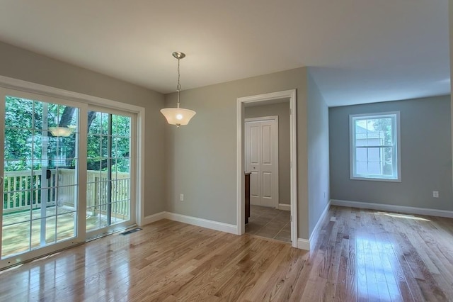 unfurnished dining area featuring light wood finished floors and baseboards