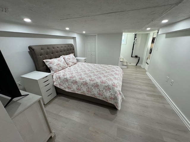 bedroom featuring light hardwood / wood-style floors and a textured ceiling