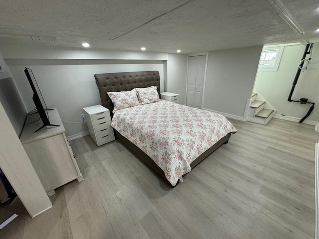 bedroom with a closet, light hardwood / wood-style flooring, and a textured ceiling