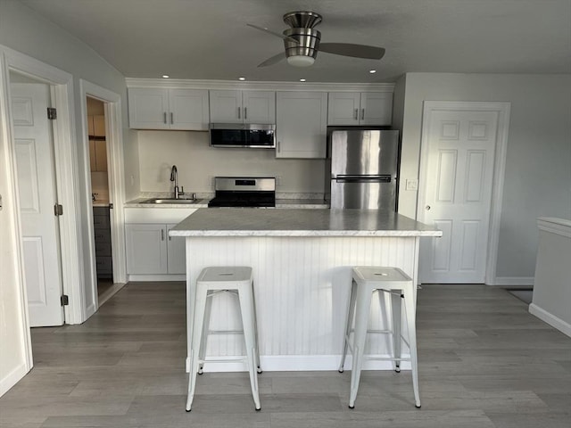 kitchen featuring a kitchen breakfast bar, white cabinetry, sink, and appliances with stainless steel finishes