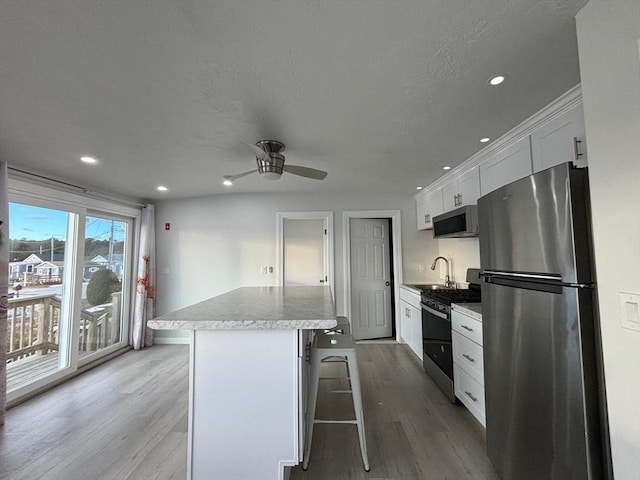 kitchen with appliances with stainless steel finishes, sink, a center island, white cabinetry, and a breakfast bar area