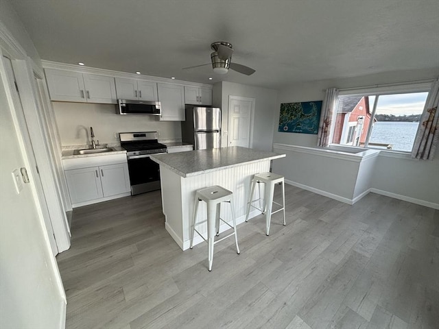 kitchen with a breakfast bar area, a center island, white cabinets, and stainless steel appliances