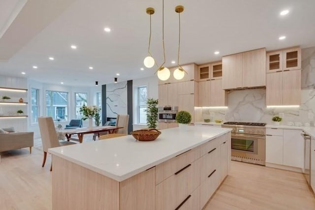 kitchen with a spacious island, modern cabinets, light brown cabinets, and high end stainless steel range