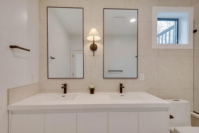 bathroom with double vanity, backsplash, a sink, and tile walls