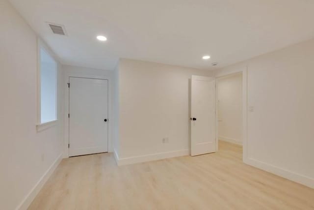 empty room with light wood-style flooring, visible vents, and baseboards