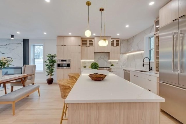 kitchen featuring stainless steel appliances, modern cabinets, a sink, and a center island