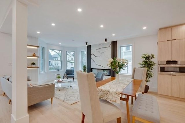 dining area featuring recessed lighting, light wood finished floors, and a premium fireplace