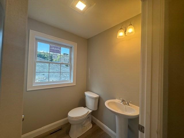 half bathroom featuring baseboards, visible vents, toilet, and wood finished floors