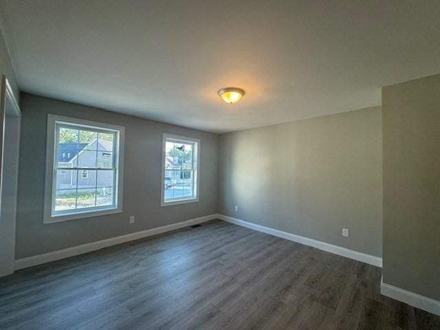 empty room featuring dark wood-style flooring and baseboards