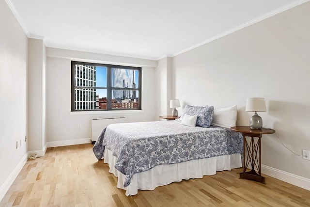 bedroom with light wood-style floors, crown molding, and baseboards