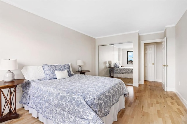 bedroom with ornamental molding, light wood-type flooring, a closet, and baseboards