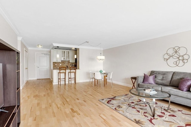 living area featuring baseboards, light wood-style flooring, and crown molding