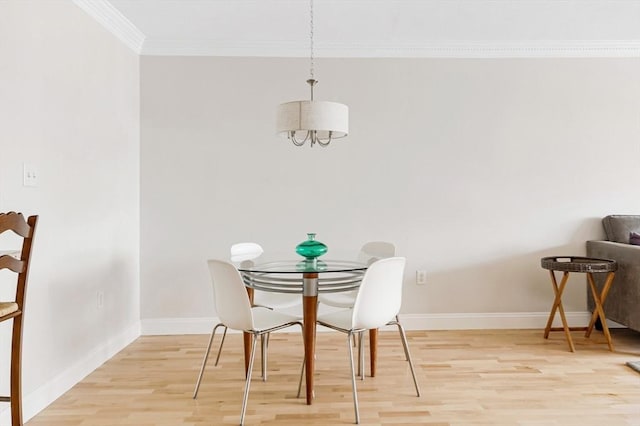 dining space with light wood-type flooring, crown molding, and baseboards