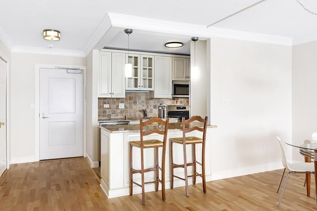 kitchen with appliances with stainless steel finishes, a breakfast bar, ornamental molding, and tasteful backsplash