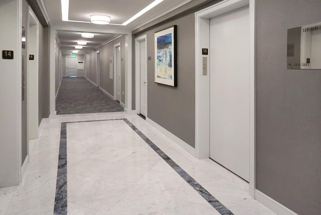 hall featuring elevator, a raised ceiling, marble finish floor, and baseboards