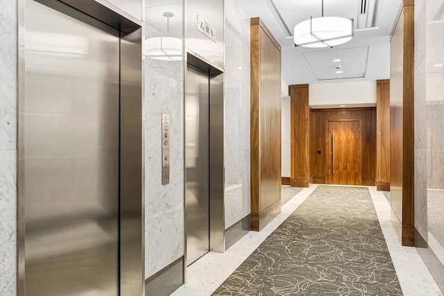 corridor featuring elevator and marble finish floor