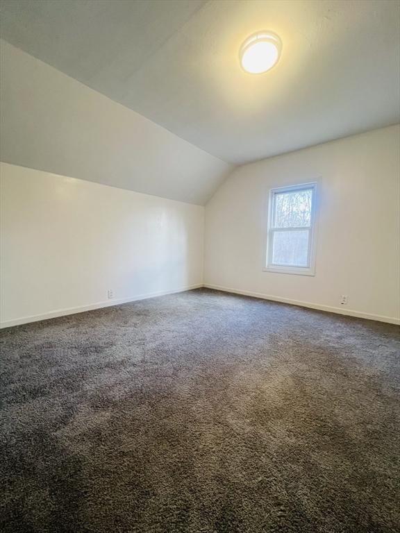 bonus room featuring lofted ceiling and dark colored carpet