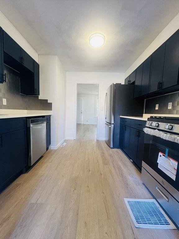 kitchen with decorative backsplash, stainless steel appliances, and light hardwood / wood-style flooring