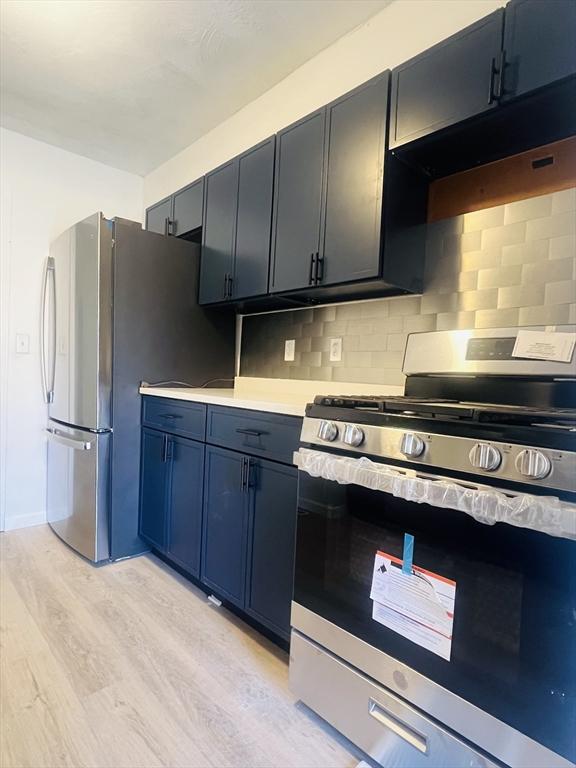 kitchen featuring light wood-type flooring, appliances with stainless steel finishes, and backsplash