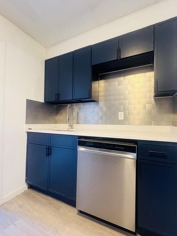 kitchen with sink, tasteful backsplash, stainless steel dishwasher, blue cabinets, and light hardwood / wood-style floors