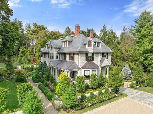 view of front of home featuring driveway, a high end roof, and a chimney