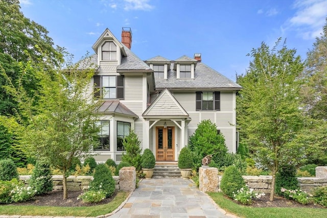 victorian house featuring a chimney and a high end roof