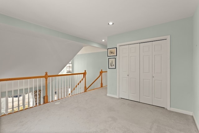 interior space featuring a closet, light colored carpet, vaulted ceiling, and multiple windows