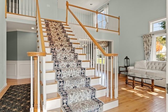 stairs with ornamental molding, a towering ceiling, and hardwood / wood-style floors