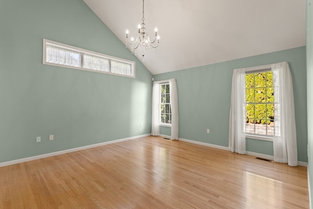 spare room with light wood-type flooring, high vaulted ceiling, and an inviting chandelier