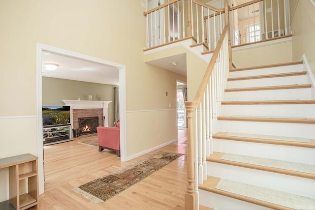 619 Pond St, Weymouth, MA 02190 - stairway with wood finished floors, a brick fireplace, a towering ceiling, and baseboards